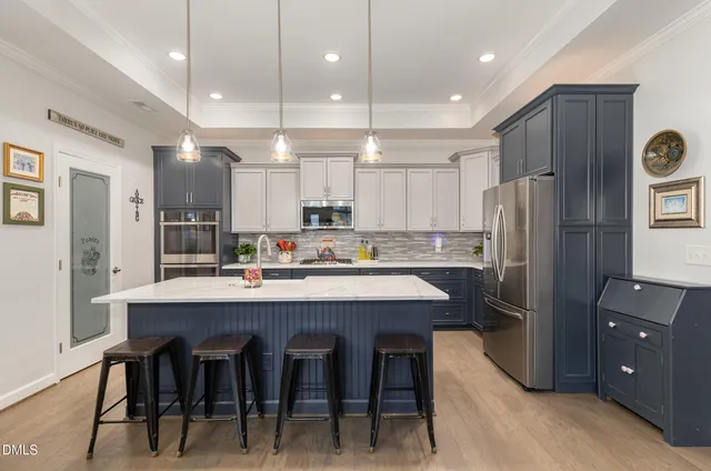 a kitchen with stainless steel appliances granite countertop a table chairs sink refrigerator and microwave