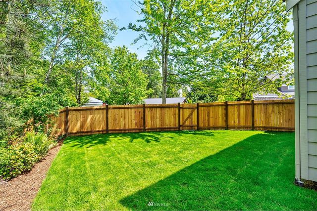 a view of a backyard with wooden fence and a large tree