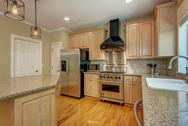 a kitchen with stainless steel appliances granite countertop a stove a sink and a refrigerator