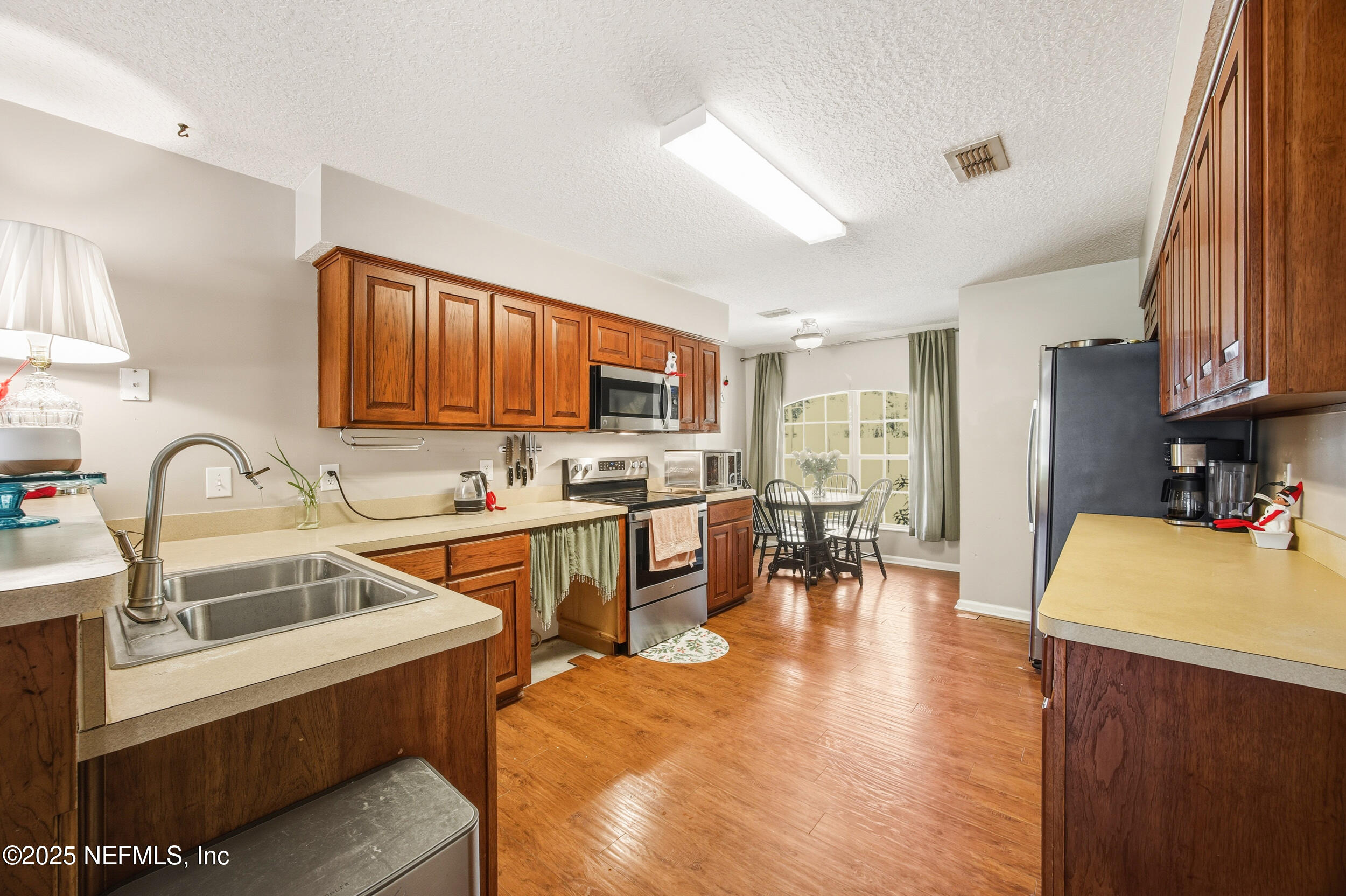 5720 Younis Road South Jacksonville, FL 32218 - Photo 27 of 34 a kitchen with stainless steel appliances granite countertop a stove top oven a sink dishwasher a dining table and chairs with wooden floor