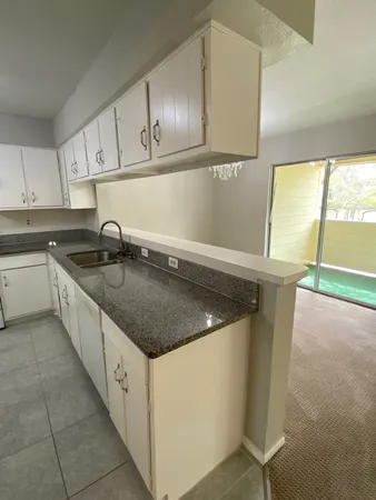 a kitchen with granite countertop a sink a stove and cabinets