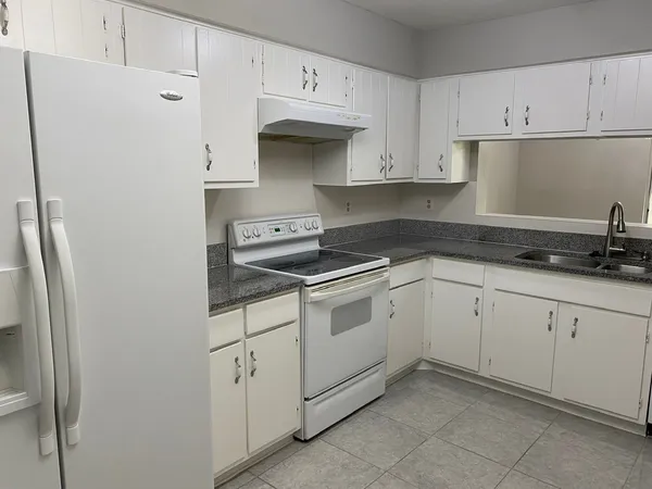 a kitchen with white cabinets and white appliances