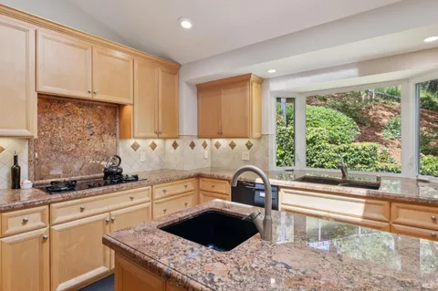 a large kitchen with stainless steel appliances granite countertop a stove a sink dishwasher and a refrigerator with wooden floor