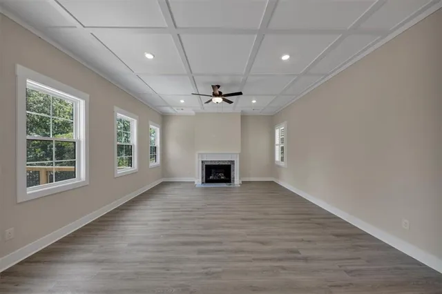an empty room with wooden floor fireplace and windows