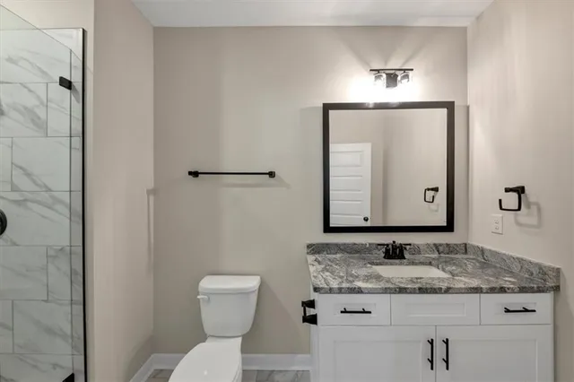 a bathroom with a granite countertop sink toilet and mirror
