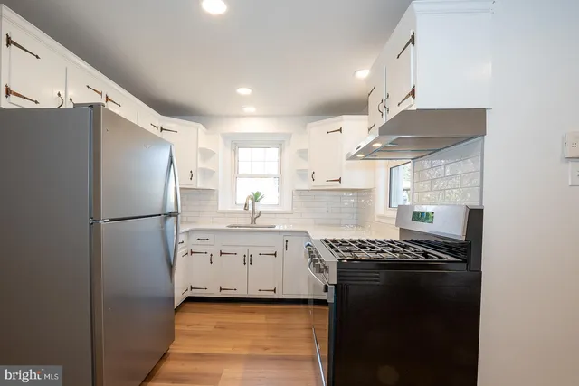 a kitchen with stainless steel appliances granite countertop a refrigerator a sink dishwasher a stove and white cabinets