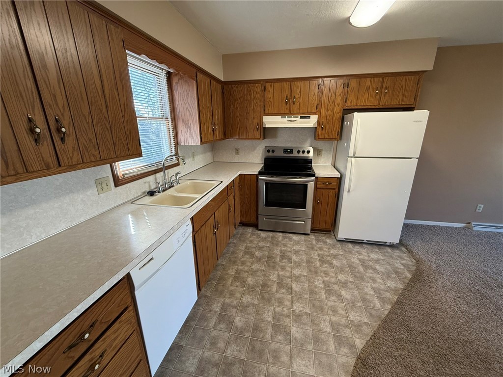 604 Harger Street Dover, OH 44622 - Photo 11 of 25 Kitchen with white appliances, light countertops, wood finish cabinets, and dark colored carpet