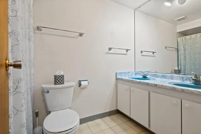 a bathroom with a granite countertop toilet a sink and a mirror