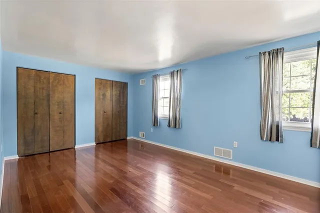 a view of an empty room with window and wooden floor