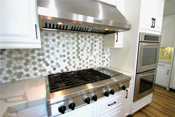a large kitchen with stainless steel appliances granite countertop a lot of counter space and wooden floors