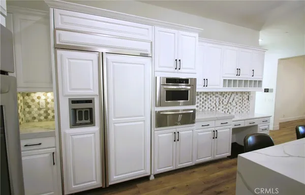 a large kitchen with stainless steel appliances granite countertop a lot of counter space and wooden floors