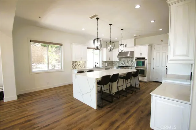 a large kitchen with stainless steel appliances granite countertop a lot of counter space and wooden floors