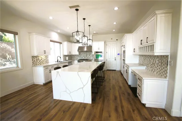a kitchen with stainless steel appliances granite countertop a sink a stove and a refrigerator