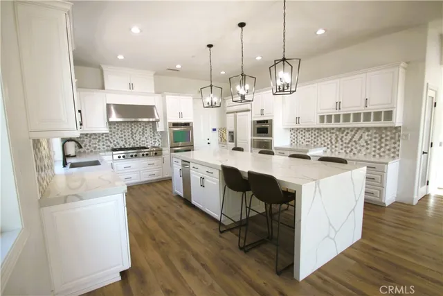 a large kitchen with stainless steel appliances granite countertop a stove a sink and a refrigerator