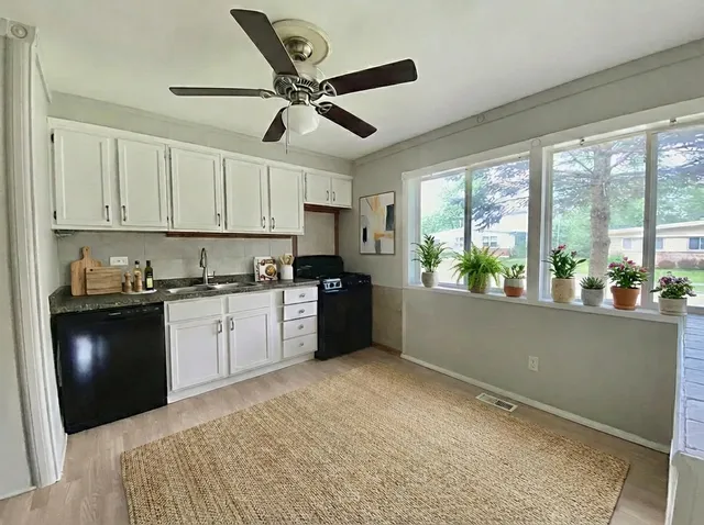 a kitchen with granite countertop a refrigerator a sink a stove and white cabinets