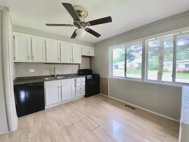a kitchen with a refrigerator and white cabinets