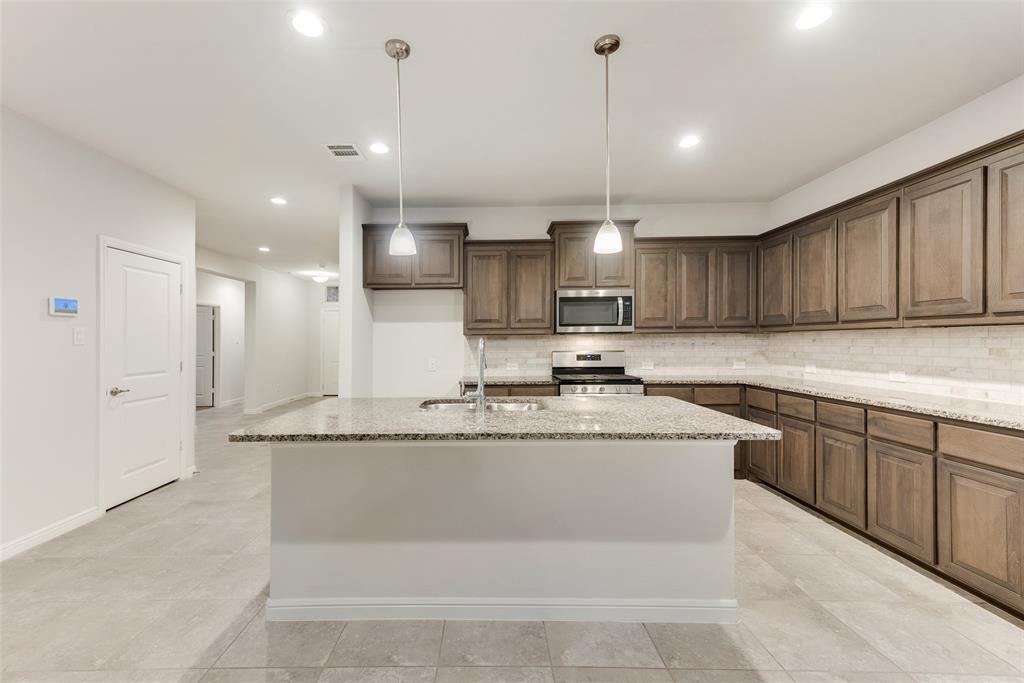 1419 Fox Hollow Road Krum, TX 76249 - Photo 12 of 29 Kitchen featuring light stone countertops, decorative light fixtures, appliances with stainless steel finishes, a kitchen island with sink, and recessed lighting