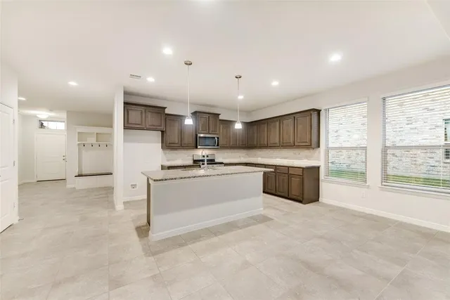 a large white kitchen with a stove a sink a refrigerator and island