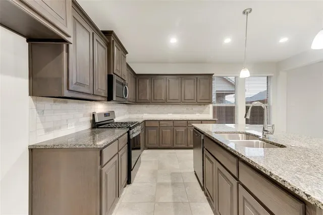a kitchen with kitchen island granite countertop a sink stove and cabinets