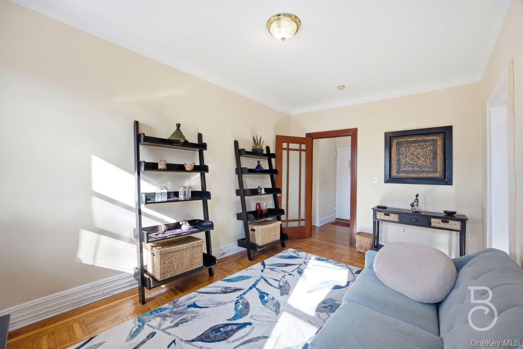 37-16 83rd Street, Unit 3F Queens, NY 11372 - Photo 3 of 11 a living room with furniture and a book shelf