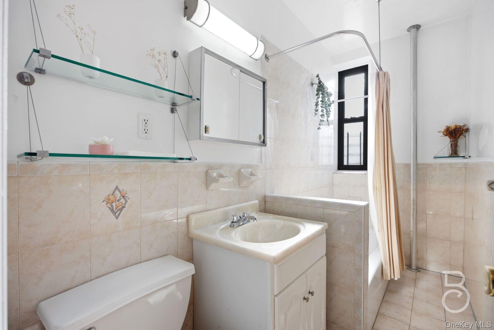 37-16 83rd Street, Unit 3F Queens, NY 11372 - Photo 5 of 11 a bathroom with a sink a toilet and shower curtain
