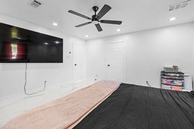 a bedroom with a large bed and a chandelier fan