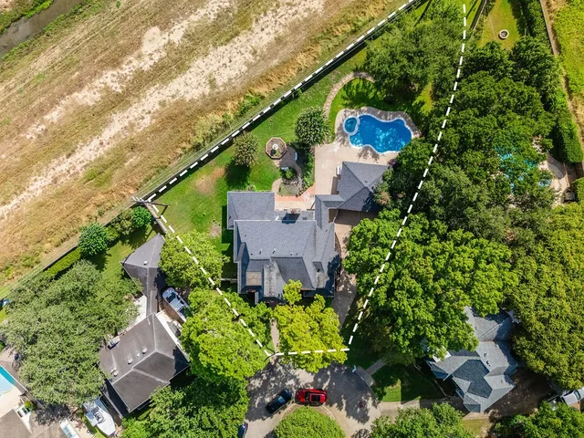 an aerial view of a house with a yard and large trees