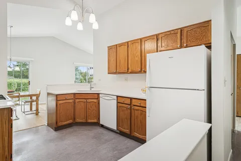 a kitchen with stainless steel appliances granite countertop a refrigerator a sink a stove a dining table and chairs with wooden floor