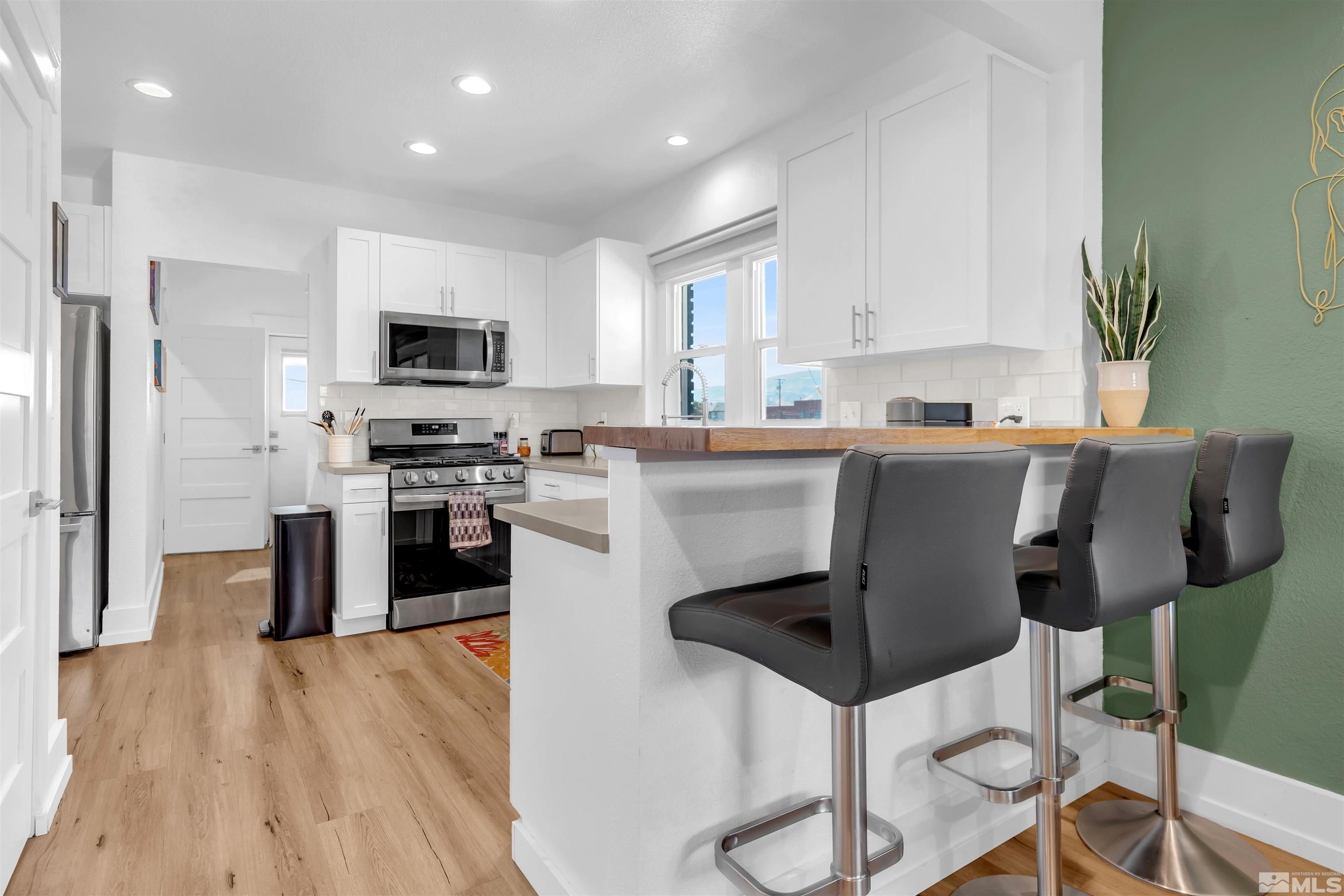 128 Stewart Street Reno, NV 89501 - Photo 5 of 24 a kitchen with stainless steel appliances granite countertop a stove top oven a sink dishwasher a refrigerator and a dining table with wooden floor