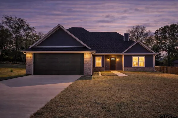 a front view of a house with yard and parking