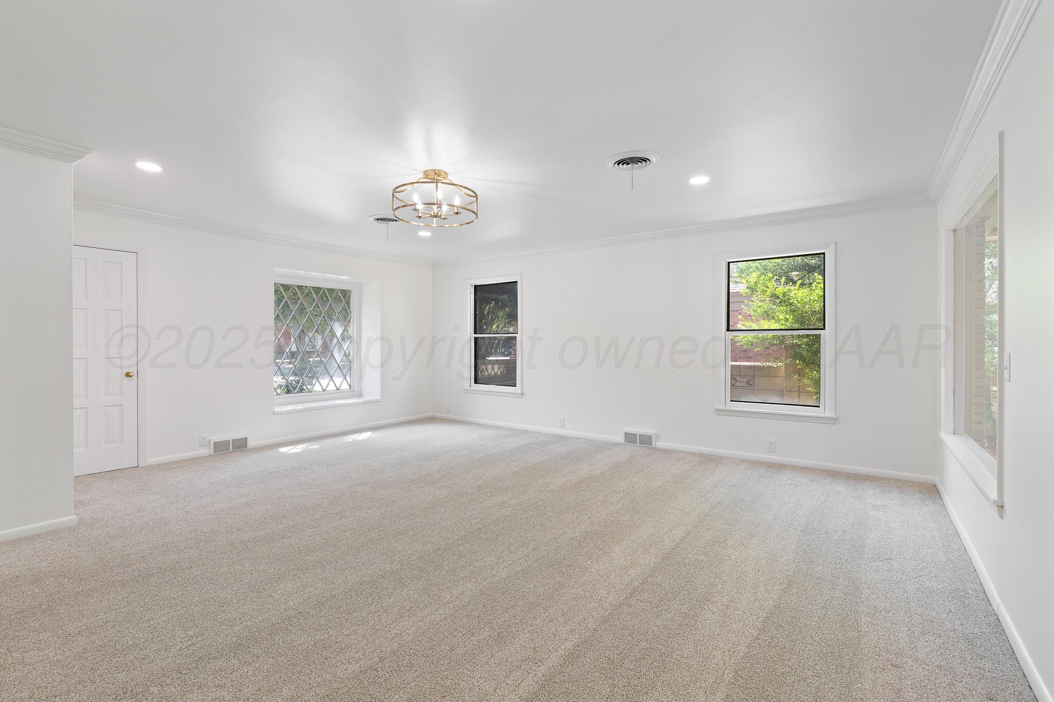 3804 Doris Drive Amarillo, TX 79109 - Photo 11 of 53 an empty room with windows and chandelier fan