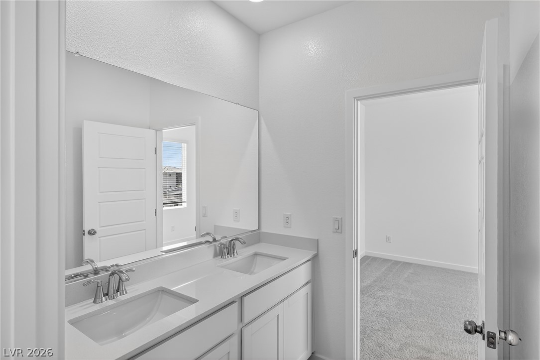 347 Sam Way Mesquite, NV 89027 - Photo 24 of 32 Double vanity sinks and bright white cabinetry elevate this modern primary bathroom.
