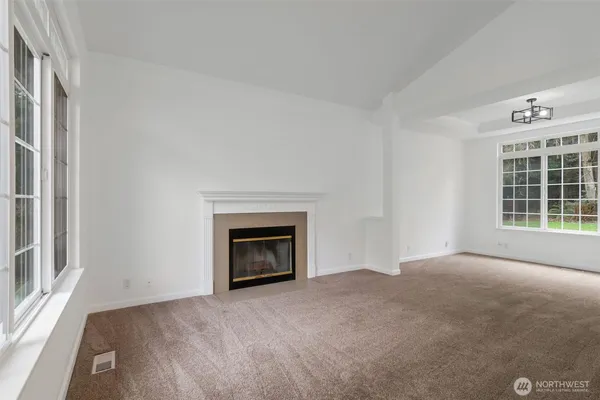 a view of an empty room with a window and fireplace