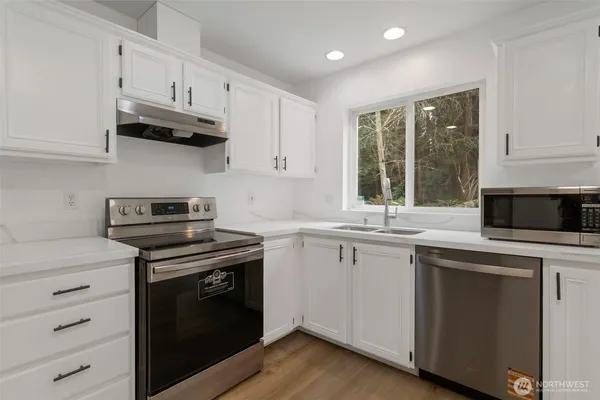 a kitchen with cabinets appliances a sink and a window