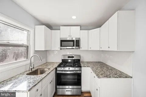a kitchen with granite countertop a sink stove and cabinets