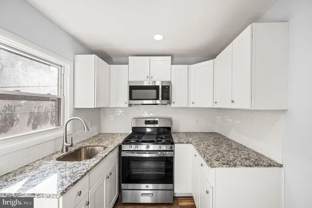 a kitchen with granite countertop a sink stove and cabinets