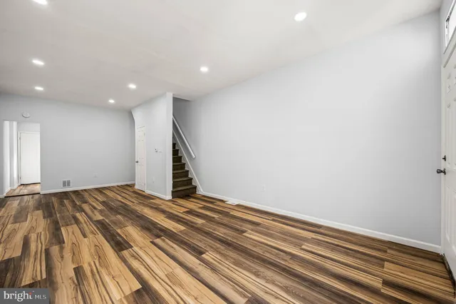 a view of an empty room with wooden floor and stairs