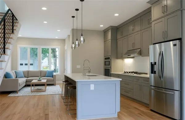 a kitchen with kitchen island a counter top space a sink stainless steel appliances and cabinets