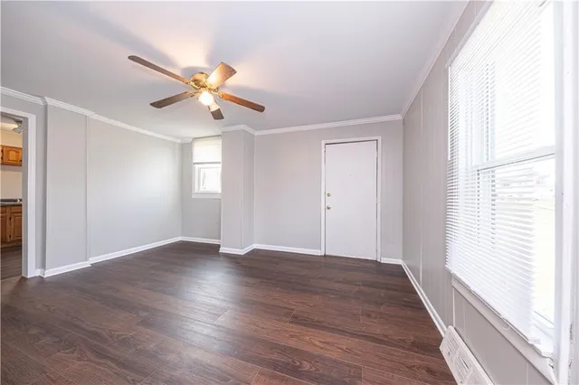 an empty room with wooden floor fan and windows