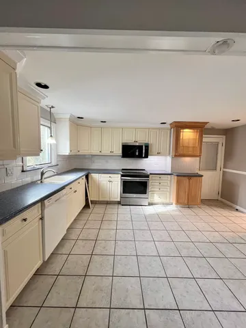 a large white kitchen with a stove top oven and cabinets