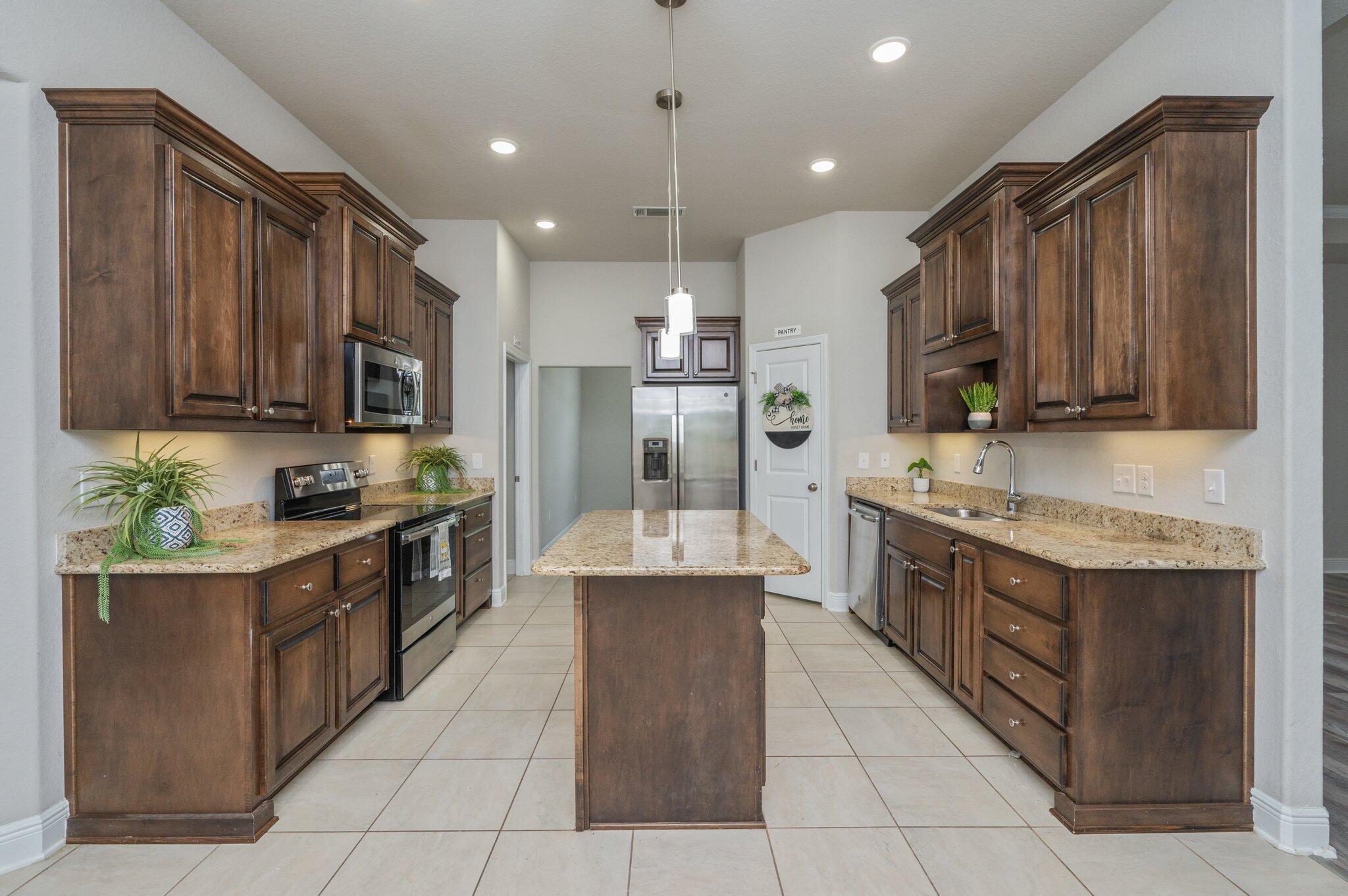 605 Terrier Trail Crestview, FL 32536 - Photo 15 of 46 a large kitchen with stainless steel appliances granite countertop a stove a sink dishwasher a refrigerator and a microwave oven