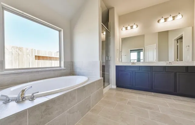 a spacious bathroom with a tub sink and mirror