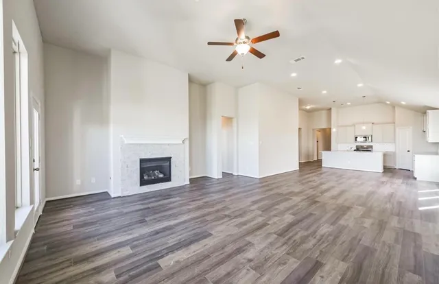 a view of a livingroom with a fireplace a ceiling fan and kitchen view