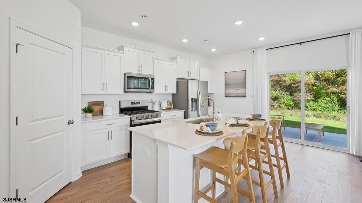 502 Scotty Boulevard, Unit 1202 Rio Grande, NJ 08242 - Photo 17 of 40 a kitchen with stainless steel appliances granite countertop a stove a refrigerator a microwave a sink and white cabinets with wooden floor