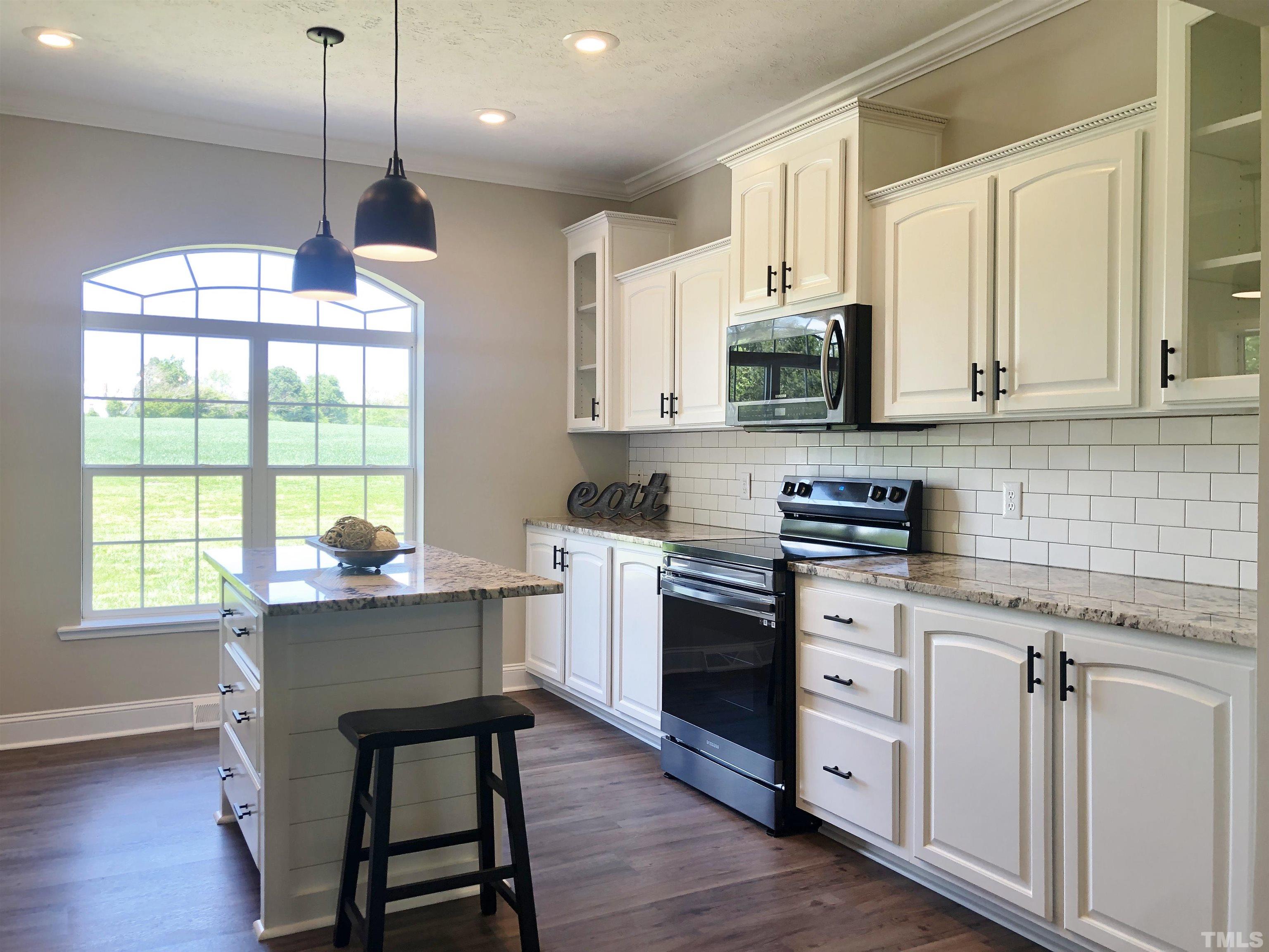 135 Satterfield Farm Road Timberlake, NC 27583 - Photo 2 of 37 a kitchen with stainless steel appliances granite countertop a stove a sink dishwasher a microwave oven and a dining table with wooden floor