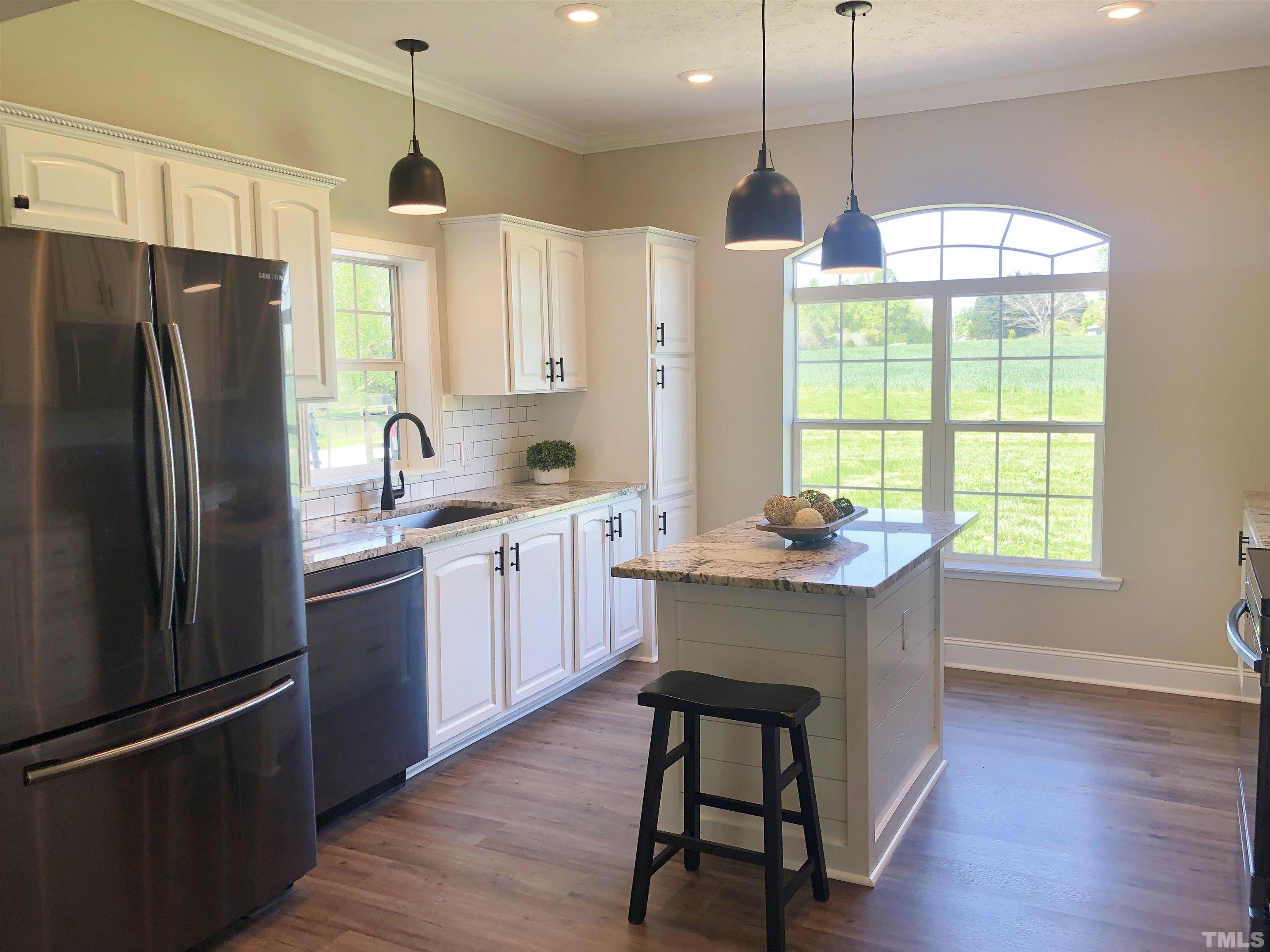 135 Satterfield Farm Road Timberlake, NC 27583 - Photo 3 of 37 a kitchen with kitchen island a wooden floor and a refrigerator