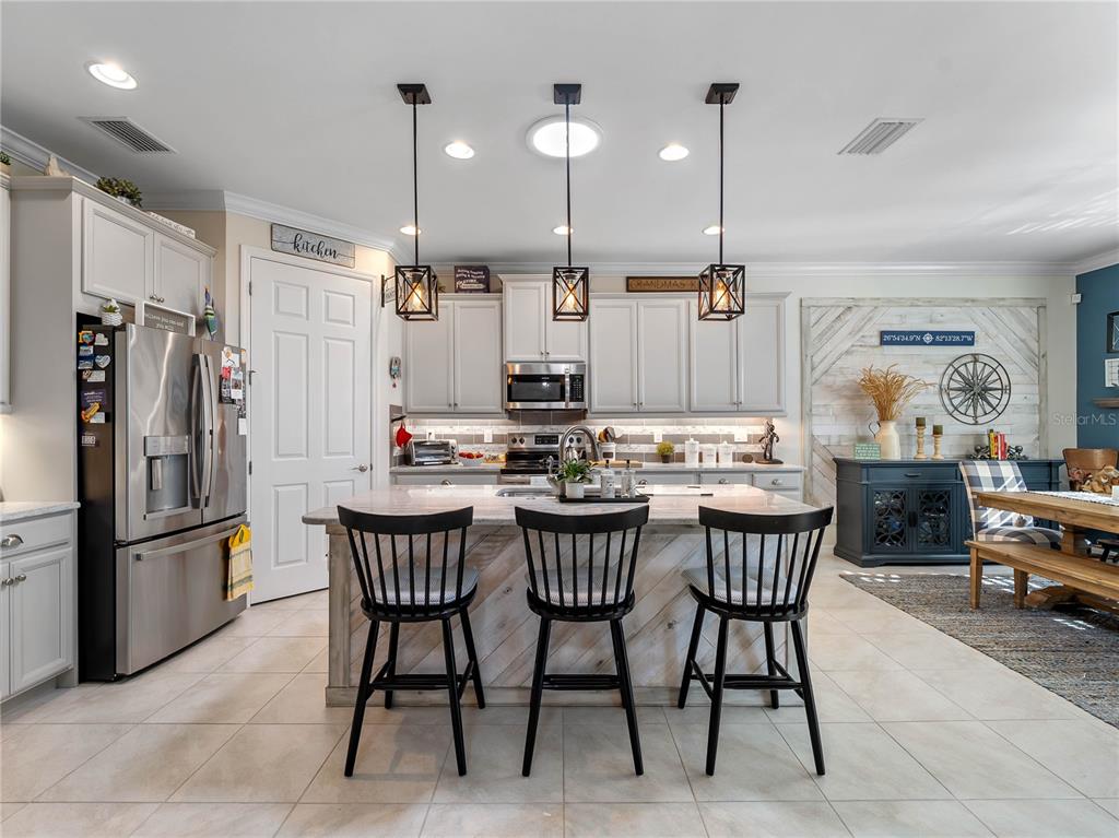 8228 Walbert Street Port Charlotte, FL 33981 - Photo 27 of 66 a kitchen with stainless steel appliances kitchen island granite countertop a dining table chairs and a refrigerator