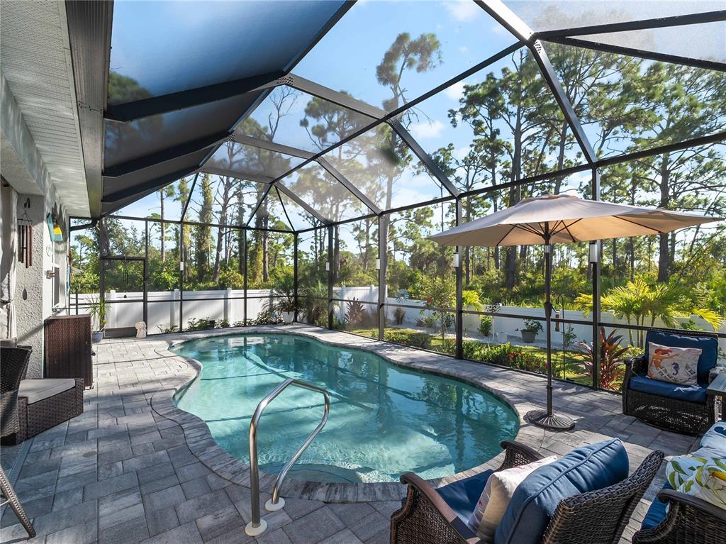 8228 Walbert Street Port Charlotte, FL 33981 - Photo 54 of 66 a view of a patio with couches table and chairs under an umbrella with a small yard