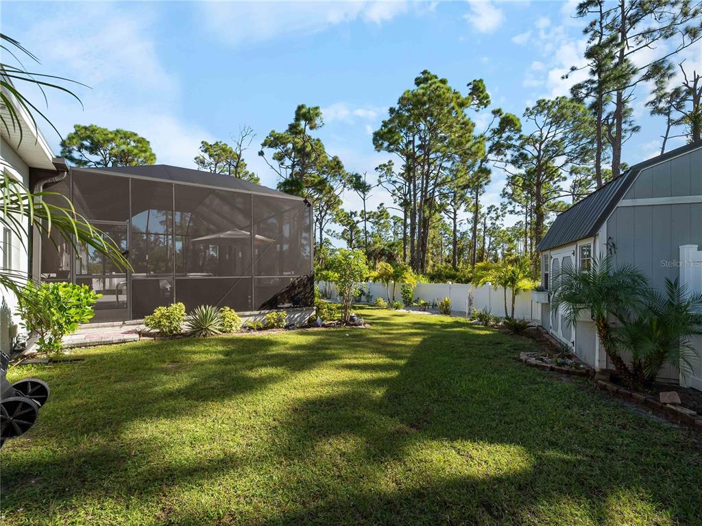 8228 Walbert Street Port Charlotte, FL 33981 - Photo 65 of 66 a backyard of a house with table and chairs plants and large tree