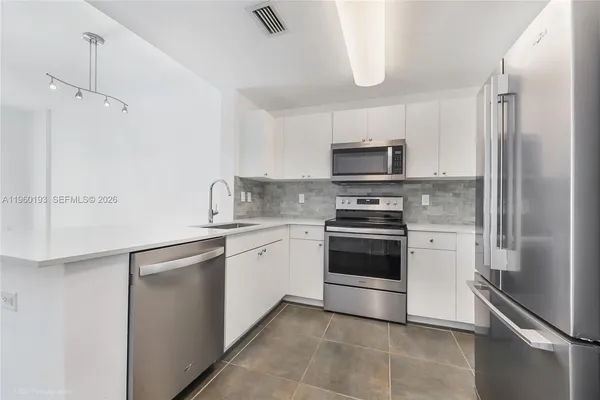 a kitchen with stainless steel appliances granite countertop a refrigerator and a stove top oven